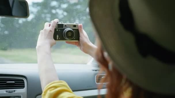 Week-end coronavirus, fille joyeuse dans un chapeau de paille et masque médical se photographie elle-même et sa famille sur un appareil photo rétro tout en voyageant en voiture en vacances après la quarantaine est levée — Video