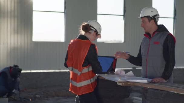 Ingenieros masculinos y femeninos discutiendo un nuevo proyecto usando una computadora portátil y dibujos — Vídeo de stock