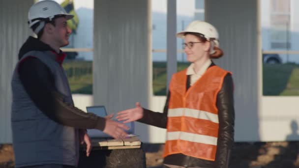 Engineer and architect in protective helmets meet each other and shake hands — Stock Video