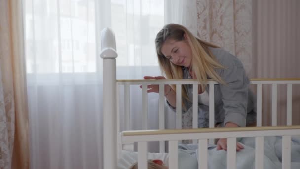 Gondoskodó szülő, boldog szerető anya lefekteti gyermekét az ágyba élvezi az anyaságot simogatja a fiát — Stock videók