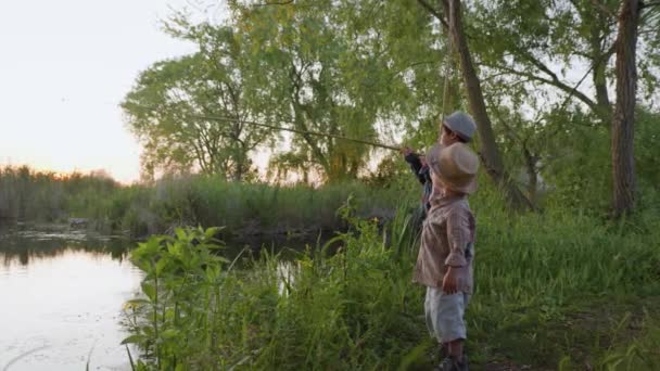 Happy childhood, healthy joyful male children enjoy summer vacation fishing on river bank at rural weekend in village — Stock Video