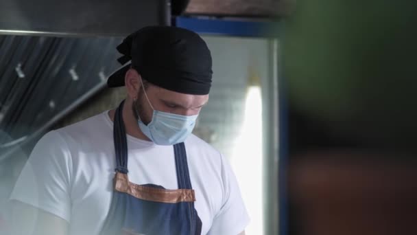 Små företag, professionell kock följer försiktighetsåtgärder coronavirus epidemi förbereder mat för cafe besökare — Stockvideo