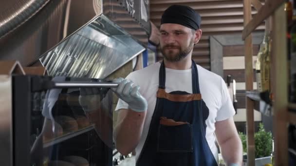 Yemek servisi, çekici erkek aşçı fırından taze ekmek alıyor. Restoran ya da kafe mutfağında hamburger yapmak için. — Stok video