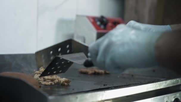 Carne grelhada, mãos masculinas com luvas virar com uma espátula de cozinha delicados pedaços picados suculentos de carne no fundo de fumaça na cozinha — Vídeo de Stock