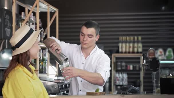 Barman bereidt heerlijke cocktail voor vrouwelijke bezoeker giet vloeistof in glas tijdens het werken in een mode-instelling achtergrond van de bar — Stockvideo