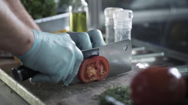 Comida rápida, chef con cuchillo de cocina rebanadas de tomate para hamburguesa sobre tabla de cortar fondo de especias y verduras en la cocina — Vídeo de stock