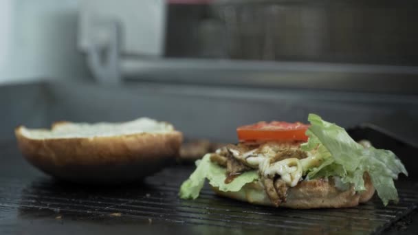 Fast food, soczysty burger z kotletem serowym i świeżą sałatą gotowaną na grillu w kuchni w kawiarni — Wideo stockowe