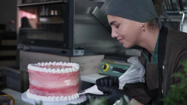 デザート幸せな笑顔のシェフ女性のペストリーシェフはペストリーバッグとタンパク質クリーム風味のパイで手作りのお祝い甘いケーキを飾りました — ストック動画