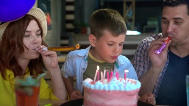 Ünneplés, férfi gyermek ünnepli születésnapját szerető szüleivel, és elfújja a gyertyákat a tortán, hangulatát ünnep — Stock videók