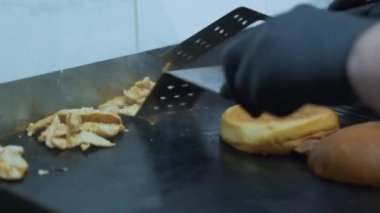 Fast food, hamburger pişirme, eldiveni olan bir aşçı lezzetli hamburgerler yapmak için et ve ekmek kızartma.