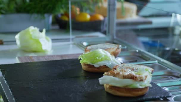 Burger et cheeseburger, petits pains chauds frais avec des feuilles de salade et de la viande hachée avec du fromage sur une plaque noire café de cuisine, restauration rapide — Video