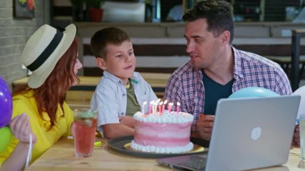 Çevrimiçi parti, mutlu güzel aile oğullarının doğum gününü kutluyor ve arkadaşlarıyla eğleniyorlar. Modern teknolojiyi bir dizüstü bilgisayar kamerasında kullanıyorlar. — Stok video