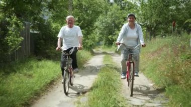 Aile yürüyüşü, yaşlı koca ve sevgili eski karısı yeşil ağaçların arasında bisiklet sürmenin keyfini çıkarıyorlar.
