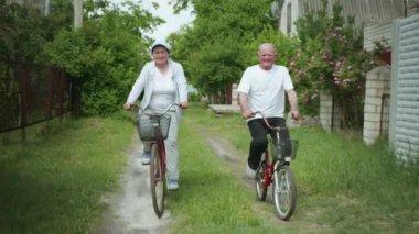 Açık hava aktiviteleri, mutlu yaşlı erkek ve kadın bisiklet sürmeyi seviyor, yaşlı neşeli bir çift bisiklet sürerken eğleniyor