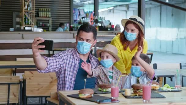 Karantänsemestrar, familj med barn iaktta säkerhetsåtgärder bära medicinska masker i ansiktet för att skydda mot virus och infektion på grund av en pandemi och coronavirus prata med vänner på en — Stockvideo