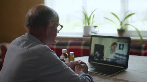 Gezondheidszorg, oudere man met een slechte gezondheid spreekt tot arts via video bellen met behulp van moderne technologie — Stockvideo