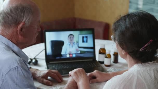 64 medicina moderna, un anciano y una anciana consultan a un médico en línea mediante una videollamada en un ordenador portátil — Vídeo de stock