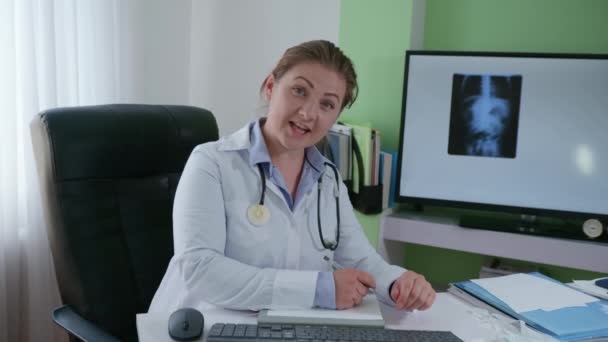 Cuidado de la salud, joven y atractiva doctora con equipo médico aconseja a los pacientes video de comunicación contra una fotografía de rayos X — Vídeos de Stock