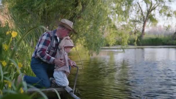 Familienurlaub, ältere fürsorgliche Großväter mit attraktivem kleinen Enkel haben Spaß beim Spielen auf dem Steg am Fluss und entspannen in der Natur — Stockvideo