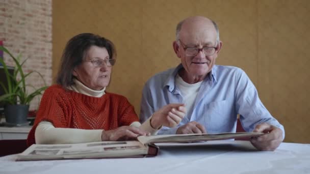 Счастливая пожилая семья, красивый муж и жена радуются, вспоминая прошедшие годы, листая фотоальбом — стоковое видео