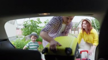 Aile gezisi, sevgili erkek çocuk bavullarıyla genç mutlu bir çift arabayla seyahat ederken bagajda.