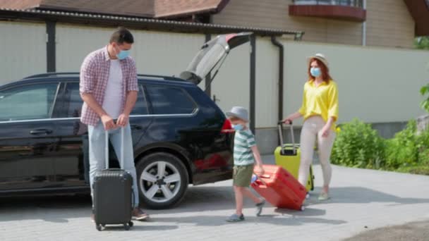 Week-end en famille, portrait de la joyeuse famille amicale dans des masques médicaux avec des valises recueillies pour aller en voyage en voiture pendant — Video