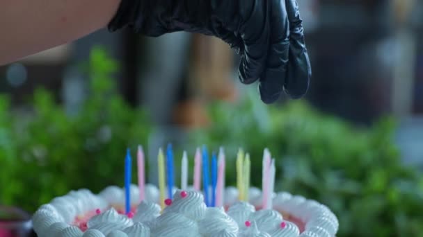 Primo piano, lo chef in guanti spruzza dolci decorazioni su torta con candele per celebrazione e compleanno di congratulazioni in caffè — Video Stock
