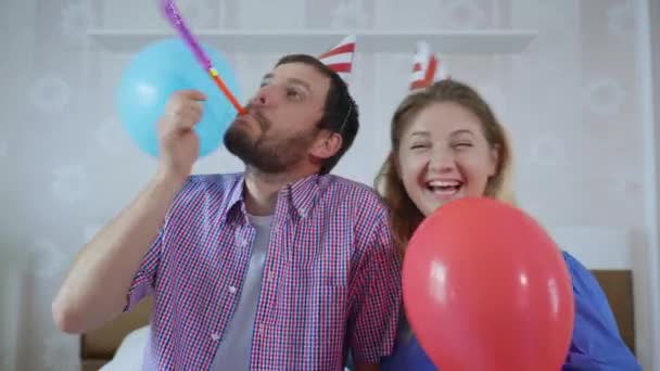 Feestjes op het netwerk, schattig grappig getrouwd paar mannen en vrouwen in hoeden met ballen en pijpen plezier met behulp van moderne technologie vieren verjaardag online met vrienden door videoconferentie op webcam op — Stockvideo