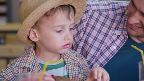 Comida de restaurante, niño pequeño disfruta de la comida rápida y jugo sentado en la mesa mientras se relaja con los padres en la cafetería, la desnutrición — Vídeos de Stock