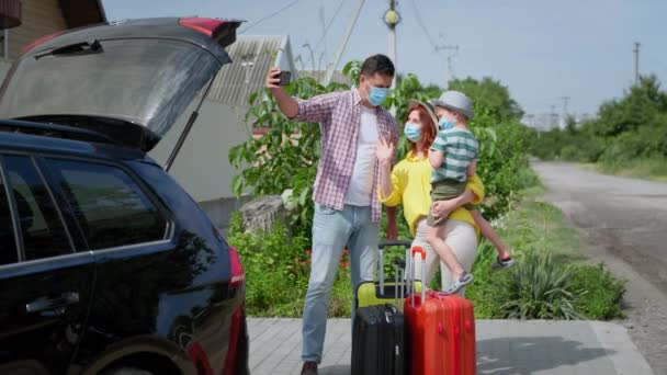 Šťastnou cestu, radostnou rodinu v lékařských maskách mluvící na smartphone v autě během vlaků — Stock video