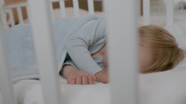 Krásný veselý bezstarostný chlapec spí a vidí šťastné sny ve svém pohodlném pytli v postýlce — Stock video