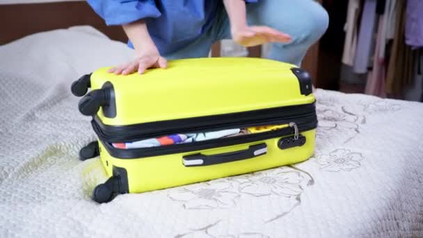 Utazási bőrönd, fiatal nő megpróbálja lezárni az ügyet a dolgok ül a tetején, és bezárja a cipzár az ő utazási táska utazás utazás — Stock videók