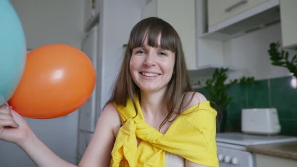 Självisolering, ung kvinna med ballonger tittar på kameran på bärbar dator och kommunicerar med vänner på distans grattis på födelsedagen — Stockvideo