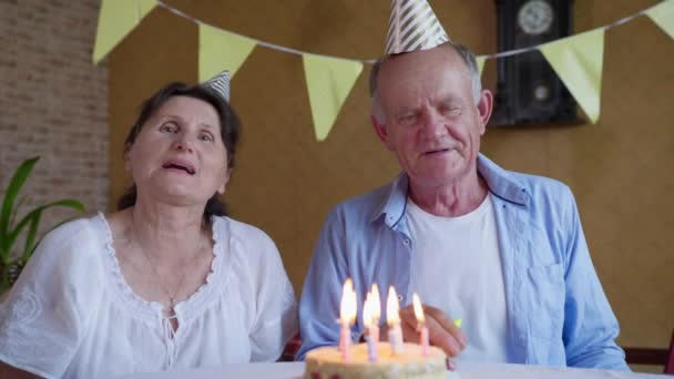Kutlama kumandası, şapkalı ve balonlu yaşlı ebeveynler ellerini çırpıyor ve bilgisayar başında aileleriyle birlikte doğum günü partisini videoya alarak kutluyorlar. — Stok video