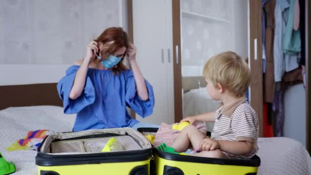 Perjalanan coronavirus, gadis cantik muda orangtua, bersama dengan anak kecil yang lucu mengumpulkan topeng medis dalam tas perjalanan — Stok Video