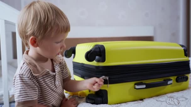 Enfance heureuse, garçon joyeux jouant avec plaisir avec une valise de voyage avec des choses zippées pour voyager — Video