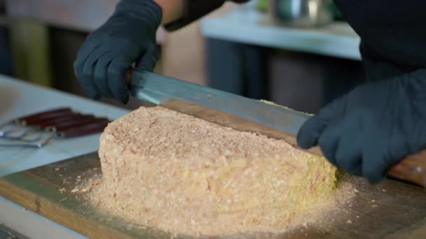 Desserts, snoepgoed in handschoenen snijdt vers gebakken taart gekookt in de bakkerij met mes, zoet voedsel — Stockvideo