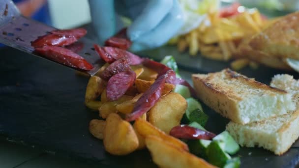 Deliciosa comida, patatas fritas fragantes con salchichas de caza y rebanadas de pan tostado en plato negro en la cocina del restaurante o cafetería — Vídeo de stock