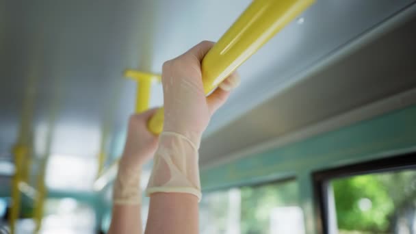 Pasajera en autobús urbano con guante médico para protegerse contra el virus y la infección se aferra a la barandilla mientras viaja en transporte público después de la liberación de la cuarentena, primer plano — Vídeo de stock