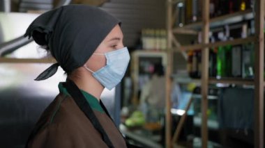 Karantinaya alınmış iş, tıbbi maske takmış yorgun aşçı ya da şekerlemeci virüsten korunmak için çok fazla iş ya da düzensiz çalışma saatleri nedeniyle alnını silmek, kameraya bakmak