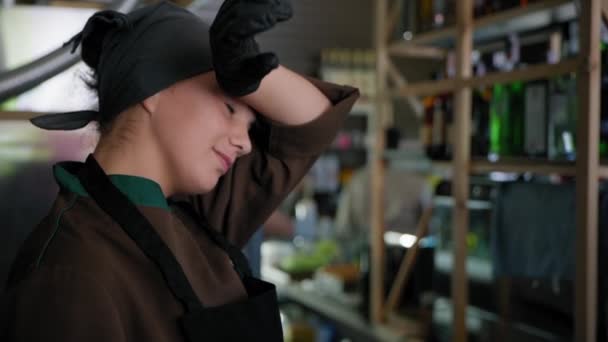 Tvrdá práce, portrét unavené zaměstnankyně kuchařky nebo cukrářky kuchařky v uniformě si rukou otírá čelo kvůli množství práce nebo nepravidelné pracovní době na pozadí kavárny nebo baru — Stock video
