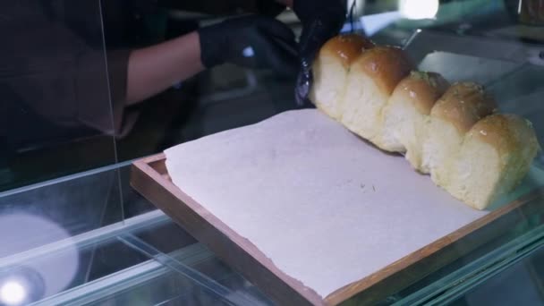 Professionele mannelijke bakker met handschoenen verspreidt verse, geurige hete broodje gemaakt van tarwebloem aan boord, kleine onderneming — Stockvideo