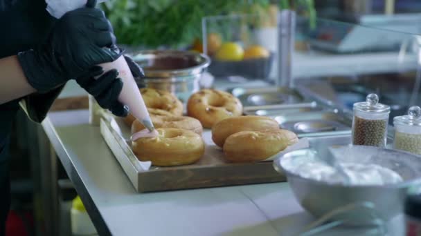 Chef-kok bakker bereidt heerlijke zoete donuts knijpt zak roomcake in de keuken van resotran of cafe — Stockvideo