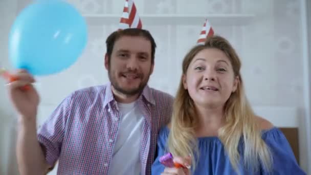 Супружеская пара в шляпах с воздушными шарами и луками поздравляют свою семью с днем рождения, глядя на веб-камеру на ноутбуке во время социальной дистанции из-за пандемии и карантина — стоковое видео