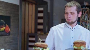 Mutlu ailenin neşeli ve aç ziyaretçilerine lezzetli hamburgerler yapar. Kafedeki kafede çocuklar eğlenir.
