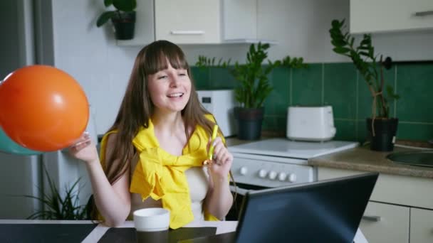 Viering online, jonge vrouw met een bal en een pijp feliciteert met zijn familie gelukkige verjaardag per video bellen op laptop tijdens sociale afstand als gevolg van pandemie en caronovirus — Stockvideo