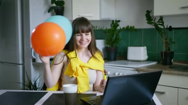 Χαρούμενο νεαρό όμορφο θηλυκό με μπαλόνια και φιόγκους μιλάμε και γιορτάζει πάρτι γενεθλίων με τους φίλους της σε απευθείας σύνδεση σε κάμερα στο φορητό υπολογιστή κατά τη διάρκεια της κοινωνικής απόστασης λόγω της πανδημίας κάθεται στο τραπέζι στο — Αρχείο Βίντεο