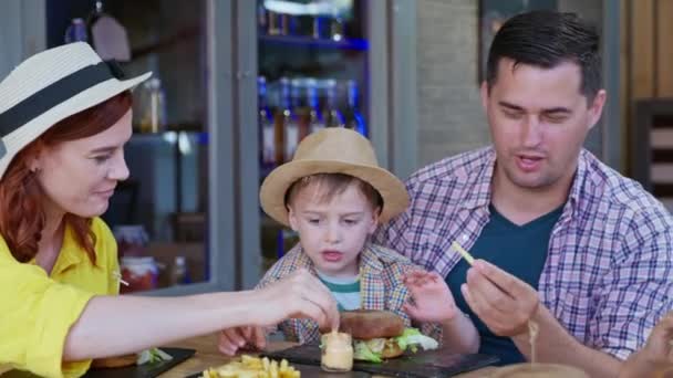 Nezdravé jídlo, krásná veselá rodina s mužskými dětmi baví jíst hranolky a hamburgery — Stock video