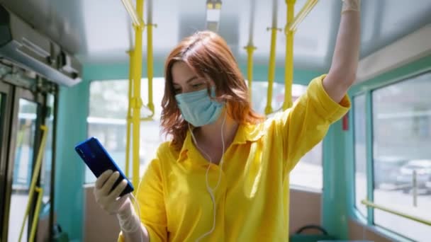 Precauciones, niña usando máscara médica para proteger contra coronavirus utiliza su teléfono inteligente mientras viaja en transporte público — Vídeo de stock