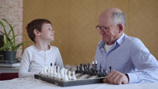Intelekt, starostlivá inteligence stařec s brýlemi pro vidění hraje deskové hry se svým chytrým vnukem — Stock video